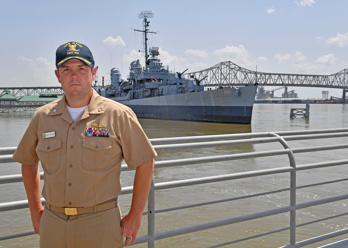 Cmdr. Matt Noland, who became the commanding officer of the current destroyer USS Kidd on May 12, 2021, stands before the original USS Kidd, on July 5, 2019, which served in World War II and is now the centerpiece of a mil World War II-era ship played role in career of destroyer Kidd’s new commander