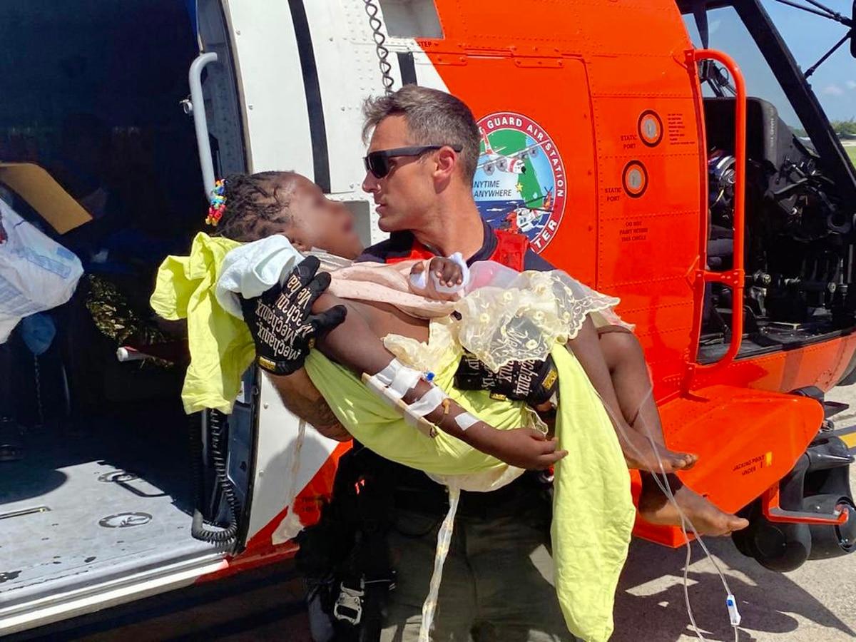 A Coast Guard air crew member helps transport a critically injured child from the helicopter to awaiting emergency medical services at Port au Prince, Haiti, Aug. 15. (Lt. David Steele/Coast Guard) US military provides assistance to Haiti following earthquake, tropical storm
