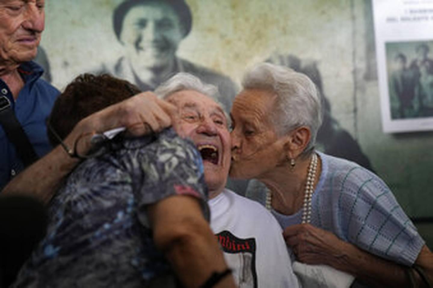 A 97 year old retired American soldier Martin Adler, center, receives a kiss by Mafalda, right, and Giuliana Naldi that he saved during a WWII, at Bologna's airport, Italy, Monday, Aug. 23, 2021. (AP Photo/Antonio Calanni) US WWII veteran reunites with Italians he saved as children