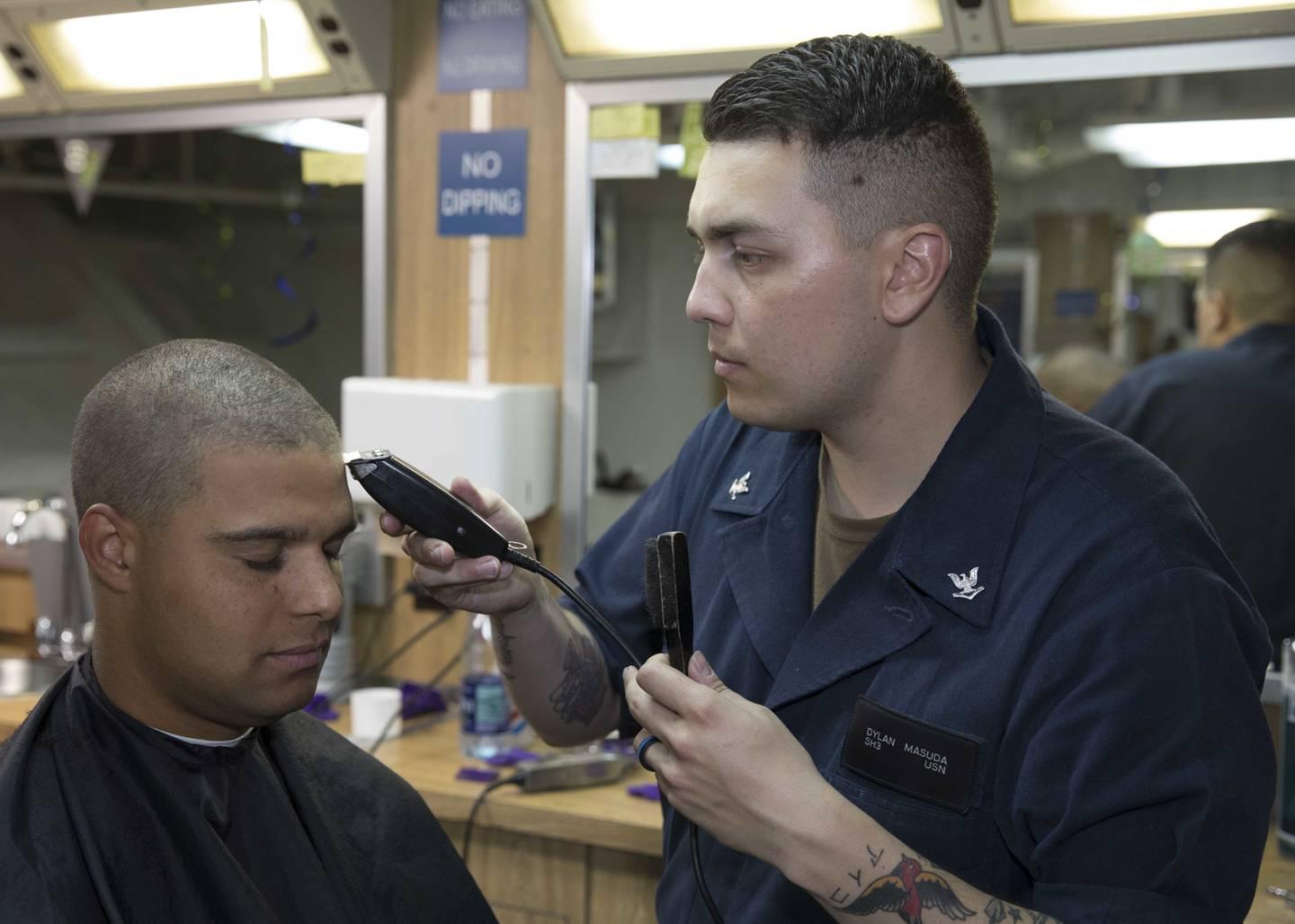 Ship's Serviceman 3rd Class Dylan Masuda cuts the hair of Hospital Corpsman 2nd Class Terence Parsons in the ship's barber shop onboard the amphibious assault ship Bataan. (MC3 Alan L. Robertson/Navy) Navy unveils series of uniform updates on hairstyle, earrings, high heels and smartwatches