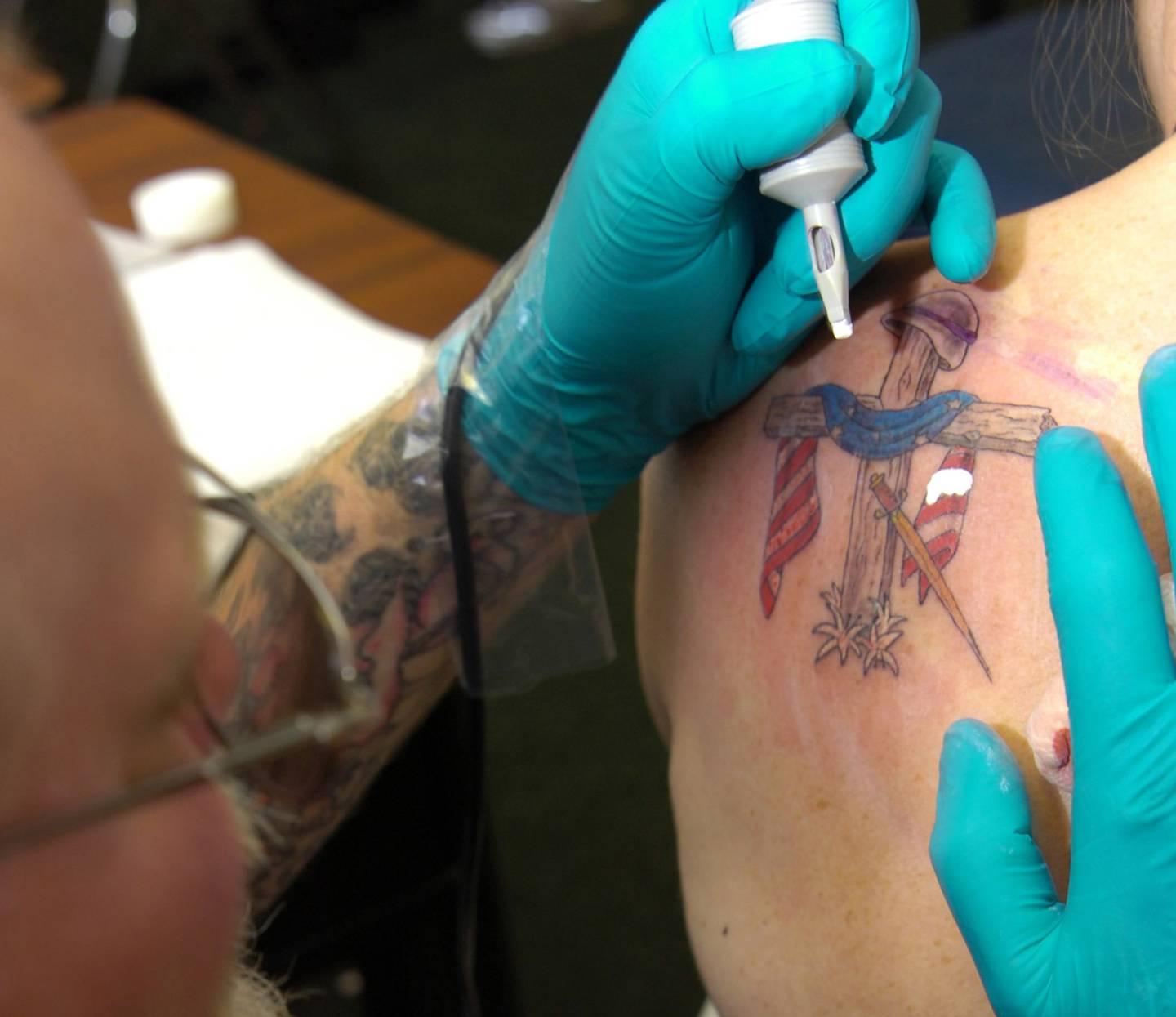 A tattoo at U.S. Naval Station Guantanamo Bay draws a picture of a cross on the shoulder blade of a service member on June 16, 2008. (Pvt. Carlynn Knaak/Army)