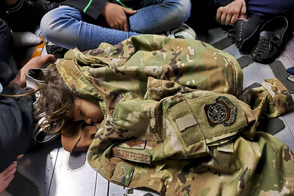 In this now-iconic photo, an Afghan child sleeps on the cargo floor of a U.S. Air Force C-17 Globemaster III carrying 823 refugees, kept warm by the Airman 1st Class Nicolas Baron's blouse during an evacuation flight from  Airman who helped with Afghan evacuations donates blouse from iconic photo