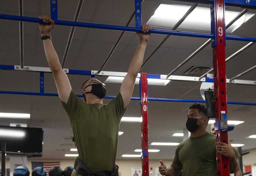 Pvt. Wyatt Hicks, left, a student with School of Infantry East, performs a weighted pullup while Sgt. Brandon Ayers, right, Alpha Company platoon sergeant, monitors his performance at the Human Performance Center on Camp G