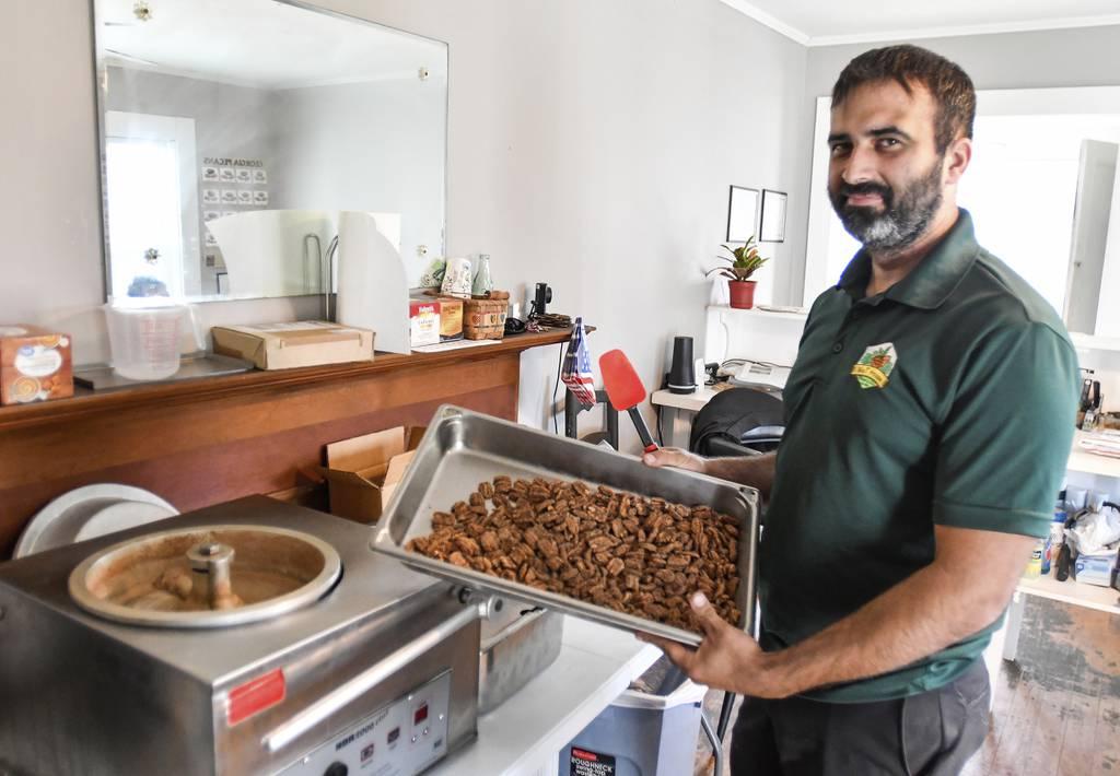 Tim Williams, owner the Nut House Pecan Company in Byron, Ga.,holds up a pan of praline pecans on Nov. 18, 2021. Williams, 32, opened a storefront in a converted old home and the Nut House Pecan Company was born. ( Jason V Disabled combat veteran opens pecan business in Georgia