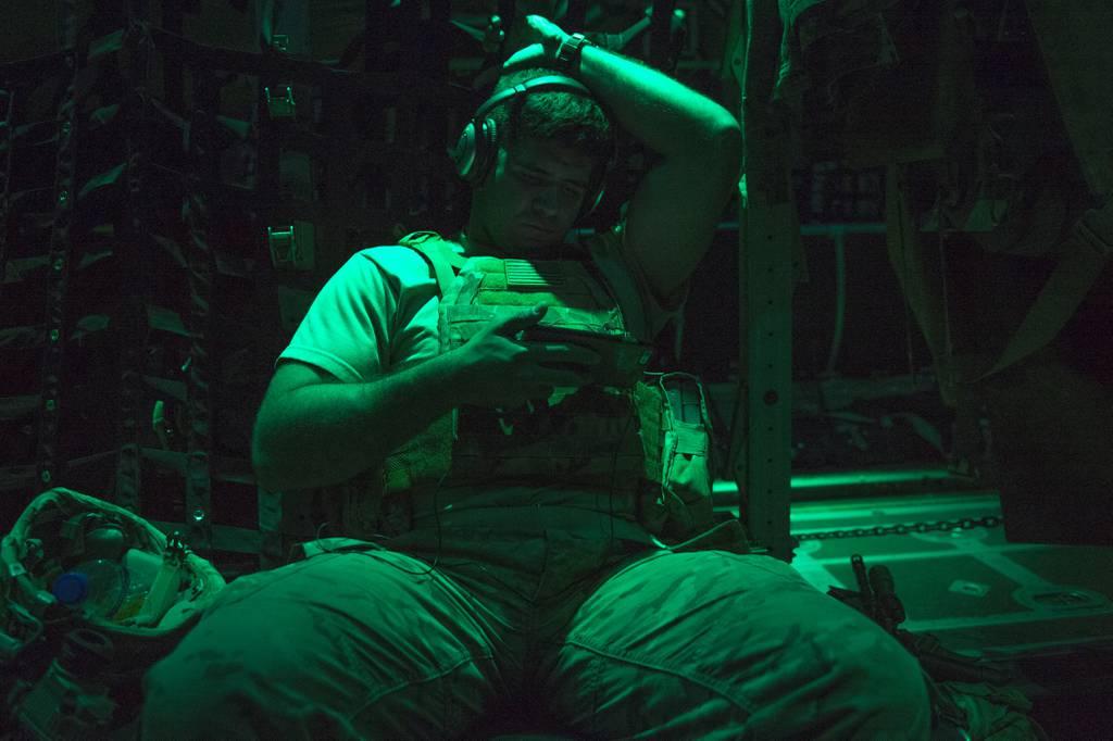 A soldier with the Task Force Hurricane 1-124 Infantry Regiment watches a movie on a personal electronic device on board a C-130J Hercules at an undisclosed location in Africa, Dec. 23, 2016. (Tech. Sgt. Joshua J. Garcia/A