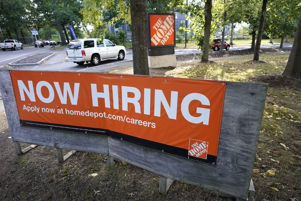The Home Depot has expanded its military discount program, which is one of its efforts to support the military. More than 35,000 employees are veterans and military spouses. Here, vehicles drive past a "now hiring" sign as