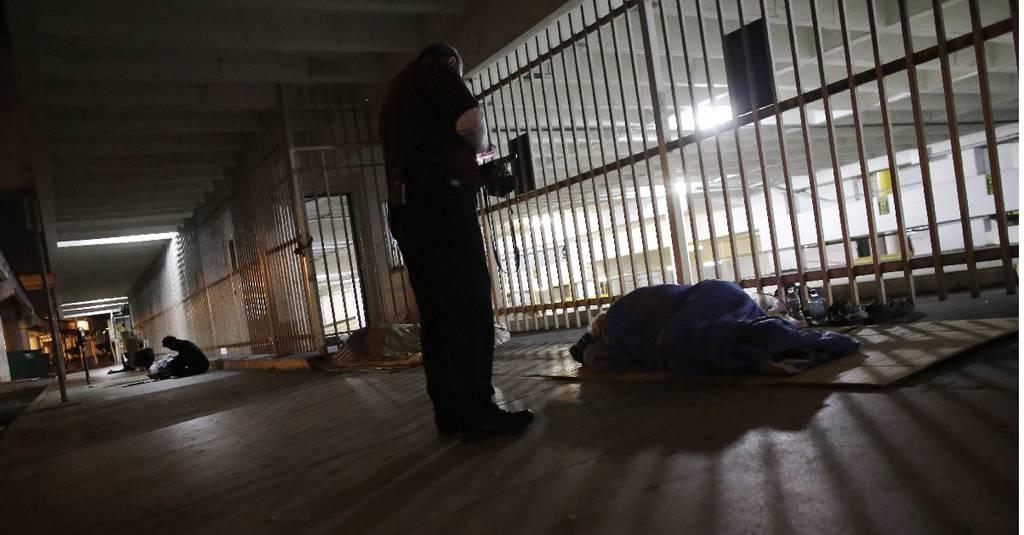 A Miami Homeless Assistance Program worker talks to a homeless person sleeping on a sidewalk during the census eevent on Jan. 23, 2015, in Miami. (Lynne Sladky/AP)