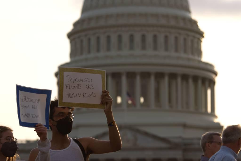 Two people wave signs — "Reproductive rights are human rights" — near the Capitol in Washington, D.C., on May 3, 2022. (Colin Demarest/C4ISRNET)