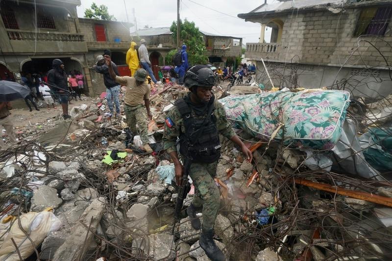 Enlarge A soldier walks over earthquake rubble Tuesday, the morning after Tropical Storm Grace ... 